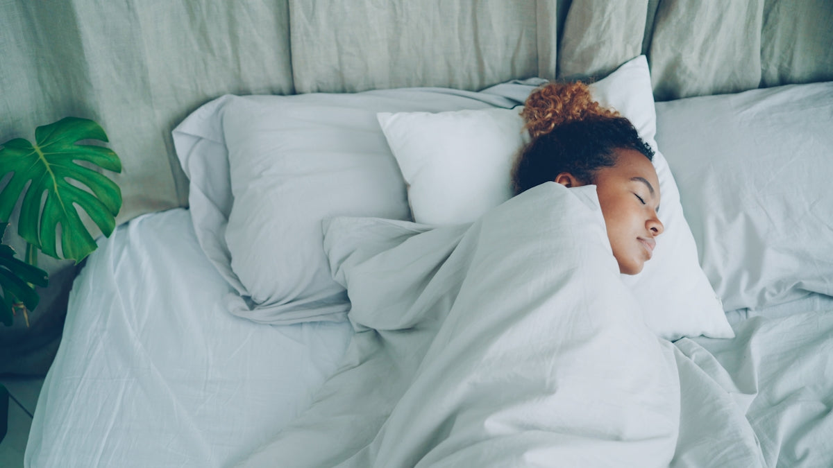 A young woman sleeping peacefully in a white bed